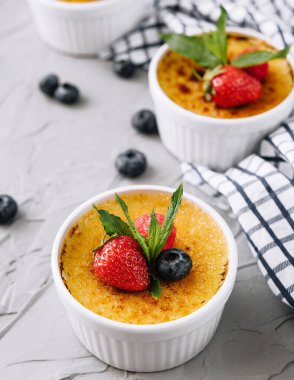cup of creme brulee with dessert plug and mint leave with berries