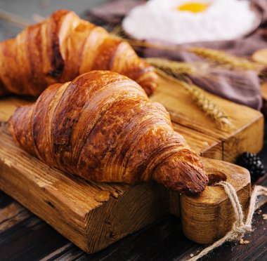 Board with tasty croissants and pastries on table