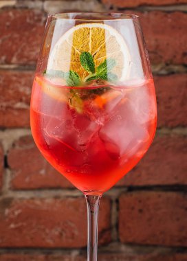 Fresh cold strawberry alcoholic drink with orange, ice and mint