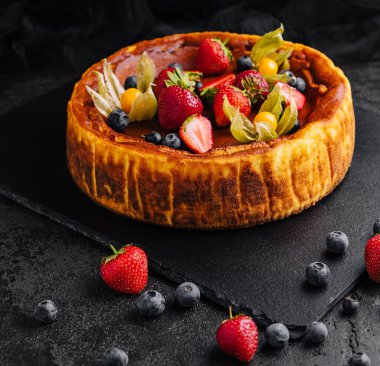 Siyah tabakta çilekli San Sebastian peynirli keki.