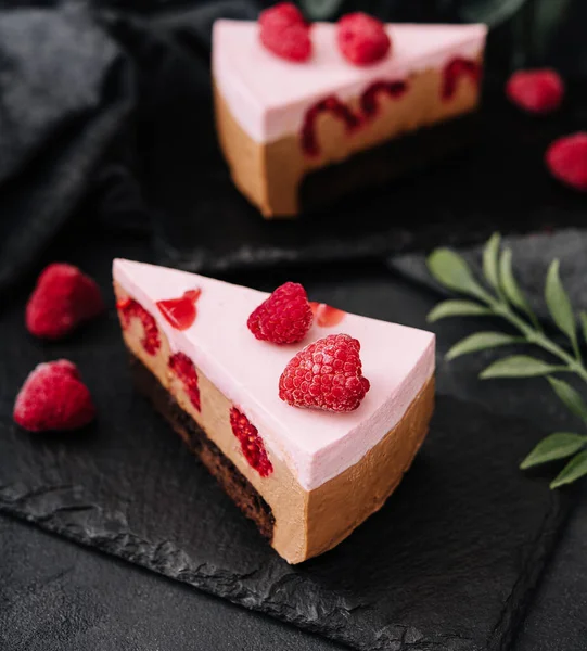 Pieces of cheesecake with raspberries on black board