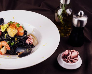 siyah beyaz tabakta su ürünleri spagetti