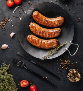 Yukarıdan siyah tavada kızarmış sosis.