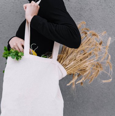 Young girl holding a cloth bag with ears of wheat