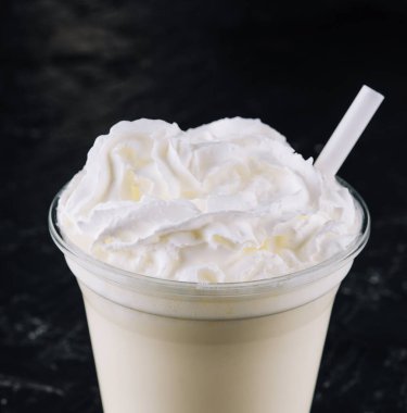 Glass with white milkshake and cream