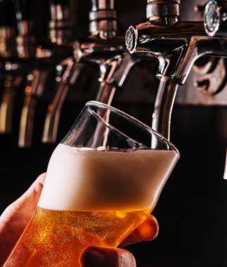 Barmen elini bira fıçısına koyup bira dökerken yakın plan.
