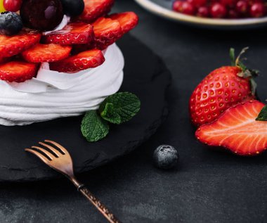 Taze böğürtlenlerle süslenmiş mini pavlova kremalı pasta.