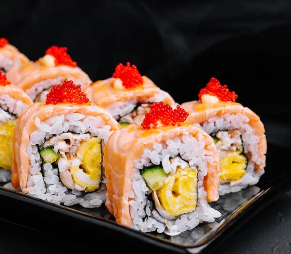 Stock image Sushi roll with fried salmon on black plate