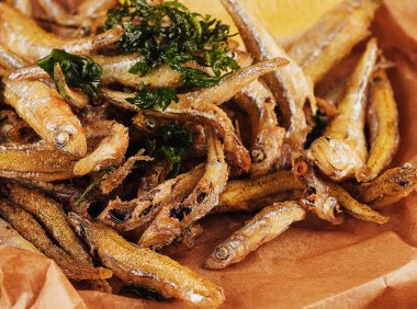 Hot fried smelt fish with salt and herbs on brown paper