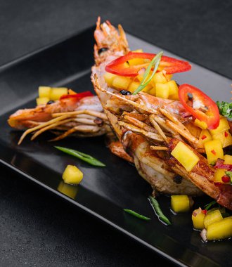 Siyah tabakta ızgara karides şişi.