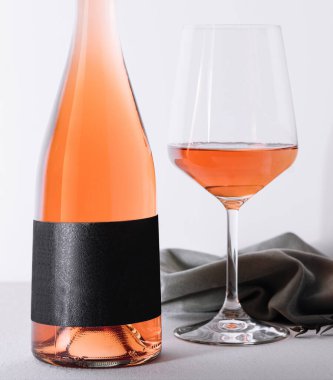 Hafif arkaplanda bir şişe gül şarabı ve cam.