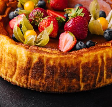 Siyah tabakta çilekli San Sebastian peynirli keki.