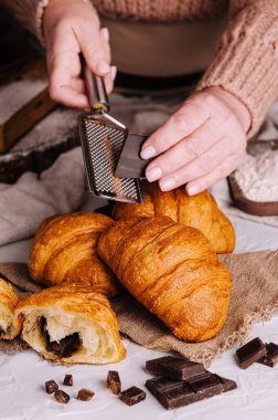 woman rubs chocolate on fresh baked croissants