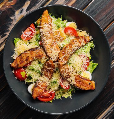 Delicious fresh salad with red fish on wooden table