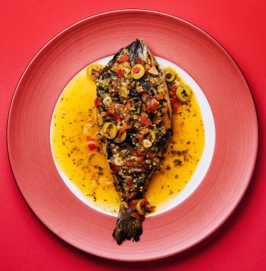 Dorado baked with special sauce on red plate