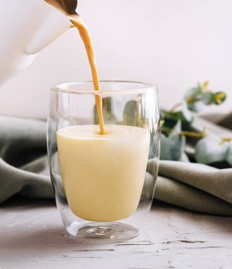 Çaydanlıktan cam fincana sütlü kahve dolduruyorum.