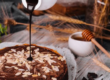 Cocoa brownies pouring with melted dark chocolate