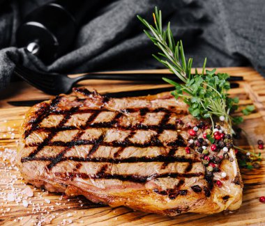 Ahşap masanın üzerinde ızgara çizgili biftek dilimlenmiş.