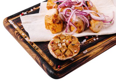 Kırmızı soğanla servis edilen tortilla üzerinde tavuk fileto şişi.