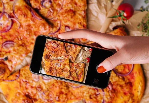 stock image Female hand making a photo of pizza with a mobile phone