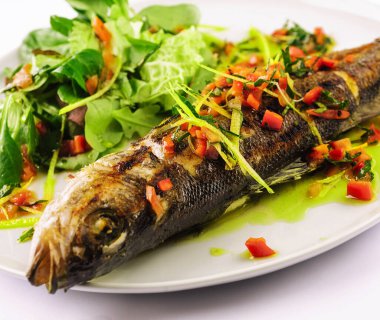 Beyaz tabakta sebzeli ızgara balık.