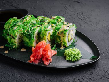 Suşi rulolarını siyah tabakta yosunların içine koy.