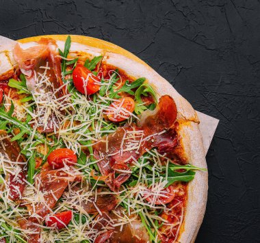 İtalyan pizzası, prosciutto, roka ve domates.