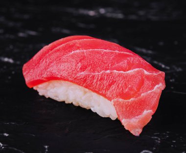 One tuna sushi on black stone background