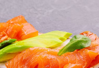 Homemade toast sandwich with salmon, avocado and basil