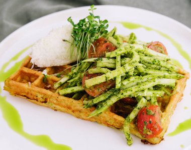 Closeup of tasty vegan potato waffle with pesto and fresh natural vegetables