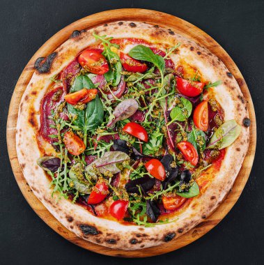 Top view pizza with salami, tomatoes and basil with arugula