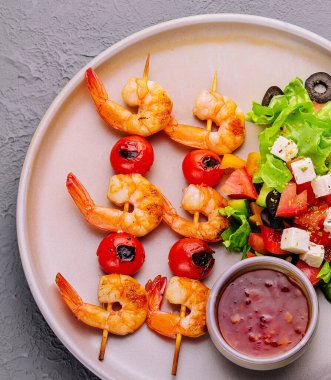 Gourmet shrimp skewers with salad greens and souce