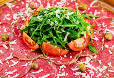 Beef carpaccio with capers, parmesan, arugula and tomatoes