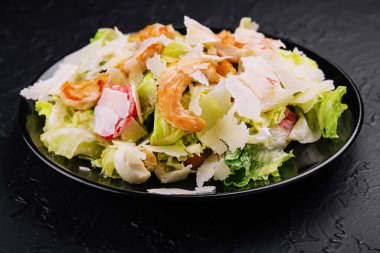 Siyah tabakta taze sezar salatası.