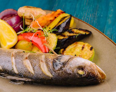 Tabakta ızgara sebzelerle pişirilmiş deniz kabuğu.