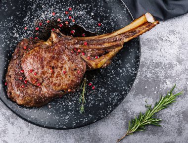 Grilled pork steak with bone in sauce on black plate