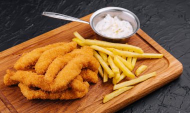 chicken nuggets and french fries on wooden board