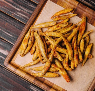 wooden board of fried whitebait with slices of lemon