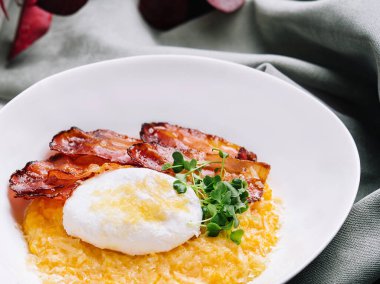 breakfast barley porridge with bacon and a poached egg