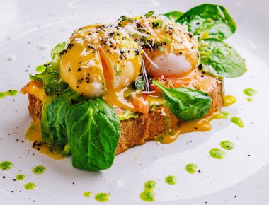 bread toast with avocado, poached egg, salmon and basil leaves