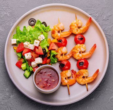 Gourmet shrimp skewers with salad greens and souce