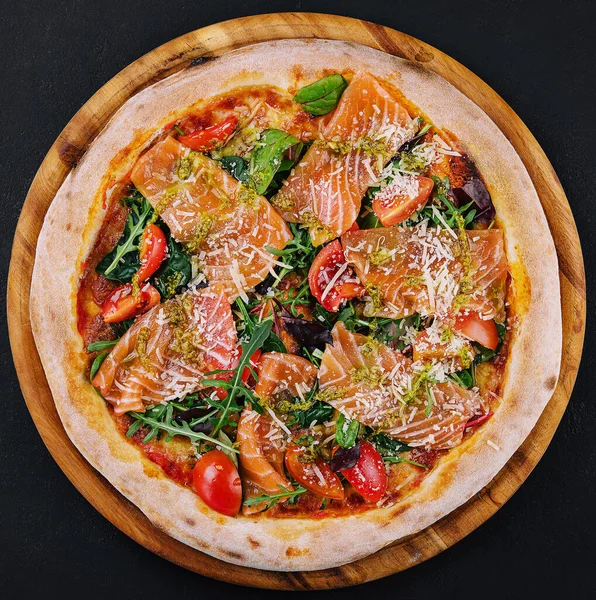 Delicious hot pizza with salmon, cheese, tomatoes and aragula