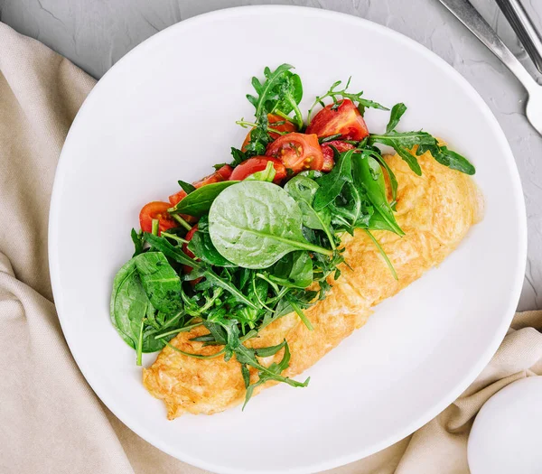 Omelet with arugula, tomatoes and basil in a plate