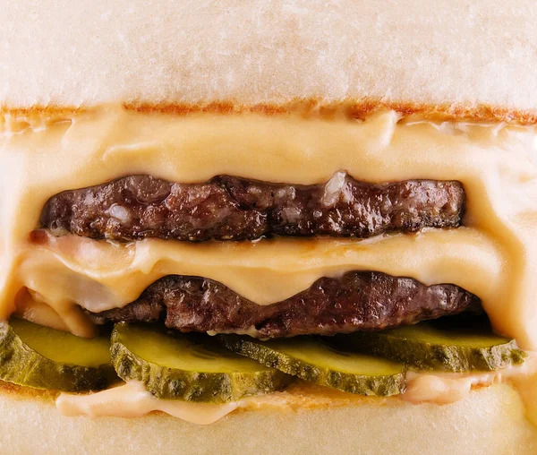 hamburger with two cutlets, pickled cucumbers and melted cheese