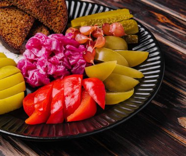 Pickles, cabbage, peppers, bread and garlic spread on a plate