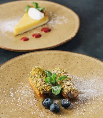 Tasty eclairs with pistachios and cheesecake on plates
