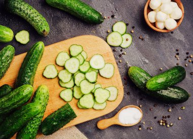 Wholes and sliced cucumbers on a wooden cutting board