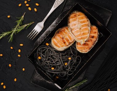 Italian salmon served over black spaghetti noodles