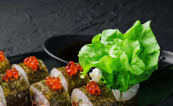 Stock image Sushi rolls served on stone slate red caviar