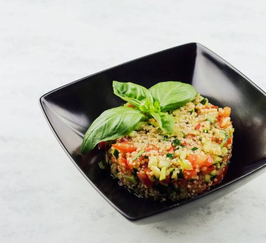 couscous tartare with vegetables in black plate